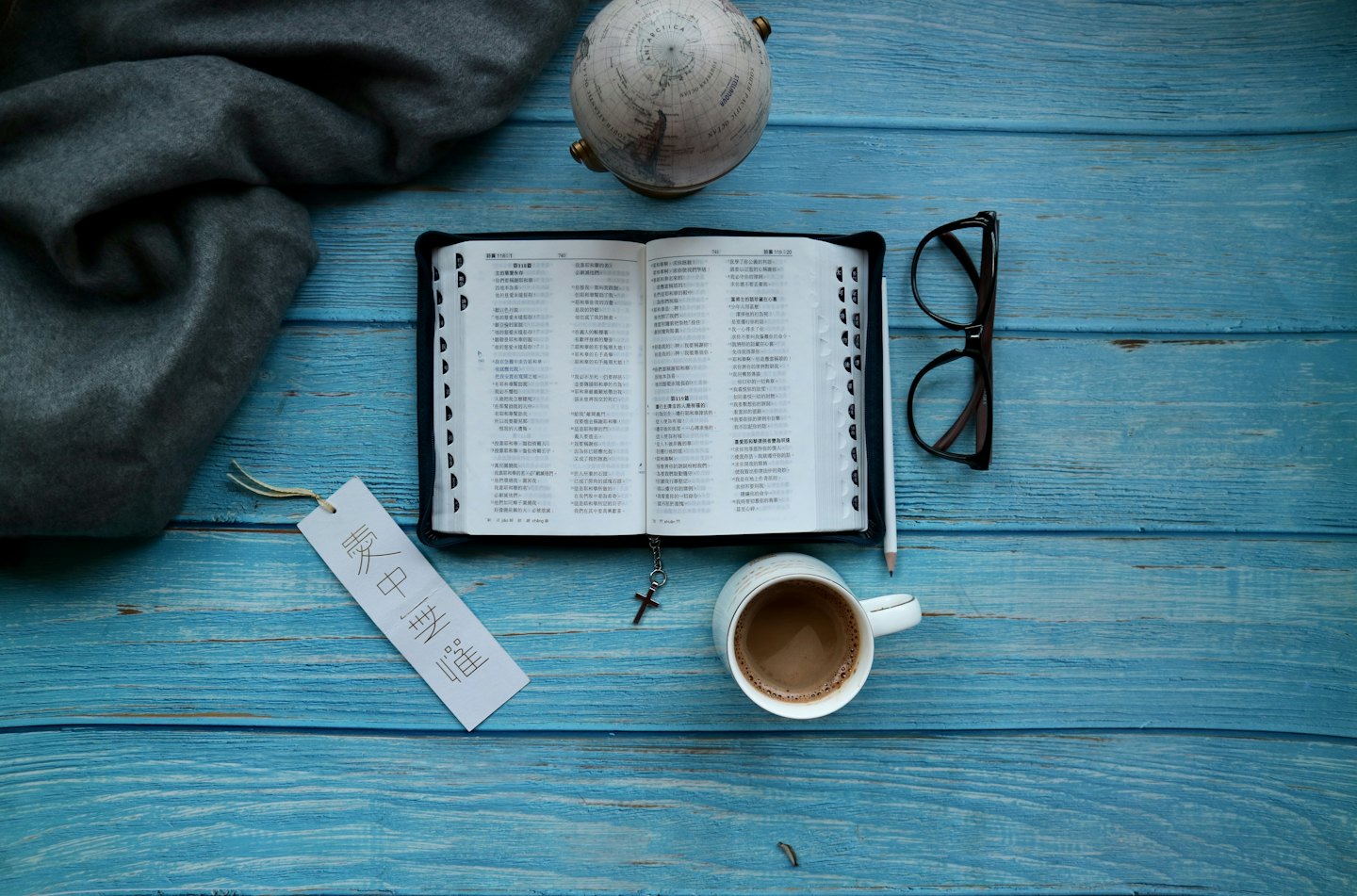 Open book, coffee mug, and glasses on a wooden table.